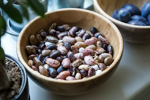 Assorted dry beans, including cranberry and white varieties, in a wooden bowl